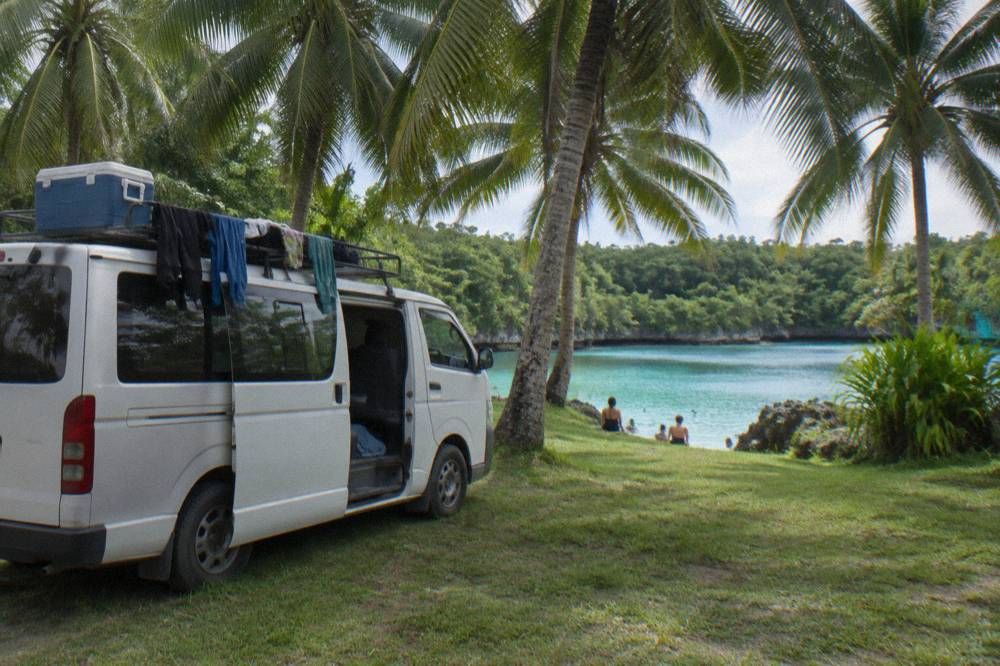 Tour van parked beside a turquoise lagoon on the Efate ring road