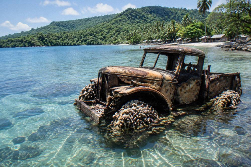 Wooden jetty over clear shallow water with forested hills behind