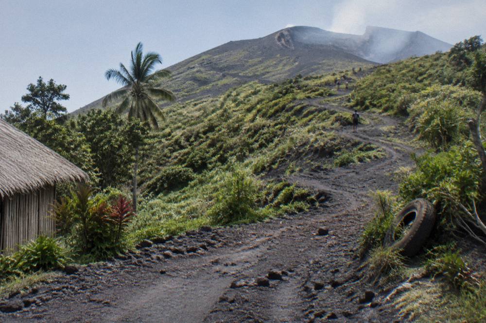 Four wheel drive track climbing through green ash-covered slopes toward the summit of Mount Yasur