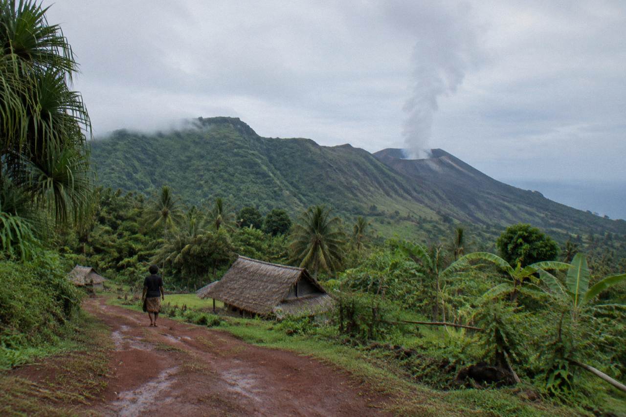 Smoke rising from a volcanic crater above green tropical hills on a Pacific island