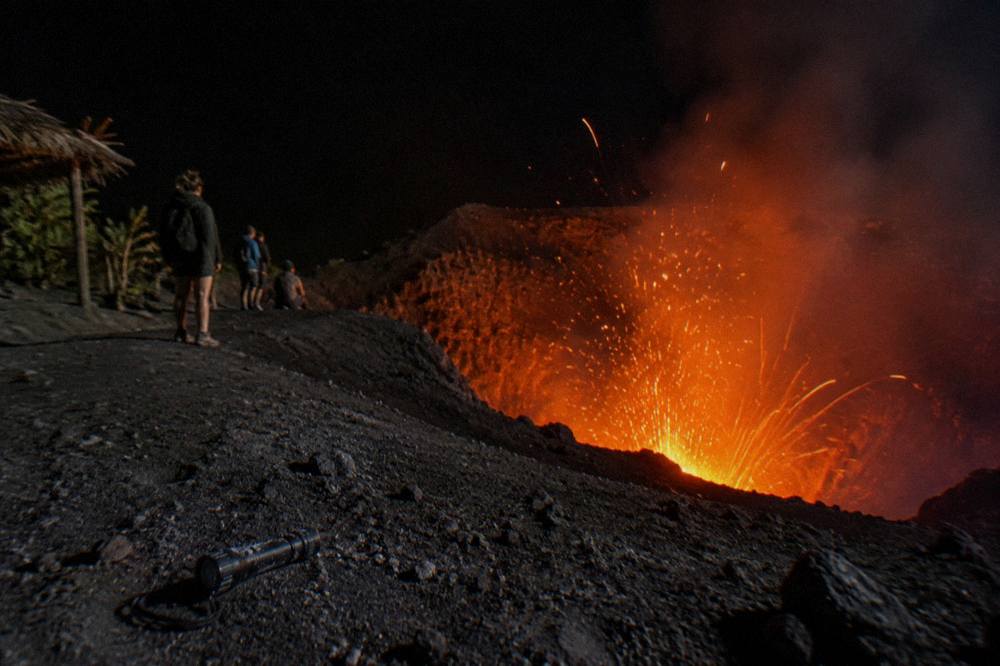 A volcanic crater glowing orange against a dark evening sky
