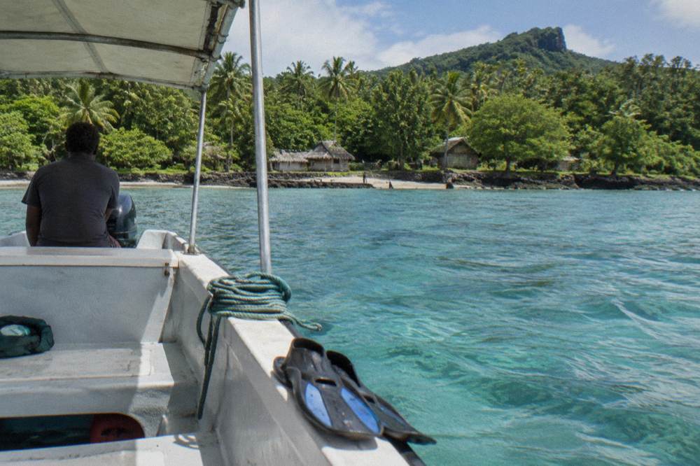 Small tour boat moored beside a turquoise lagoon with forested shoreline