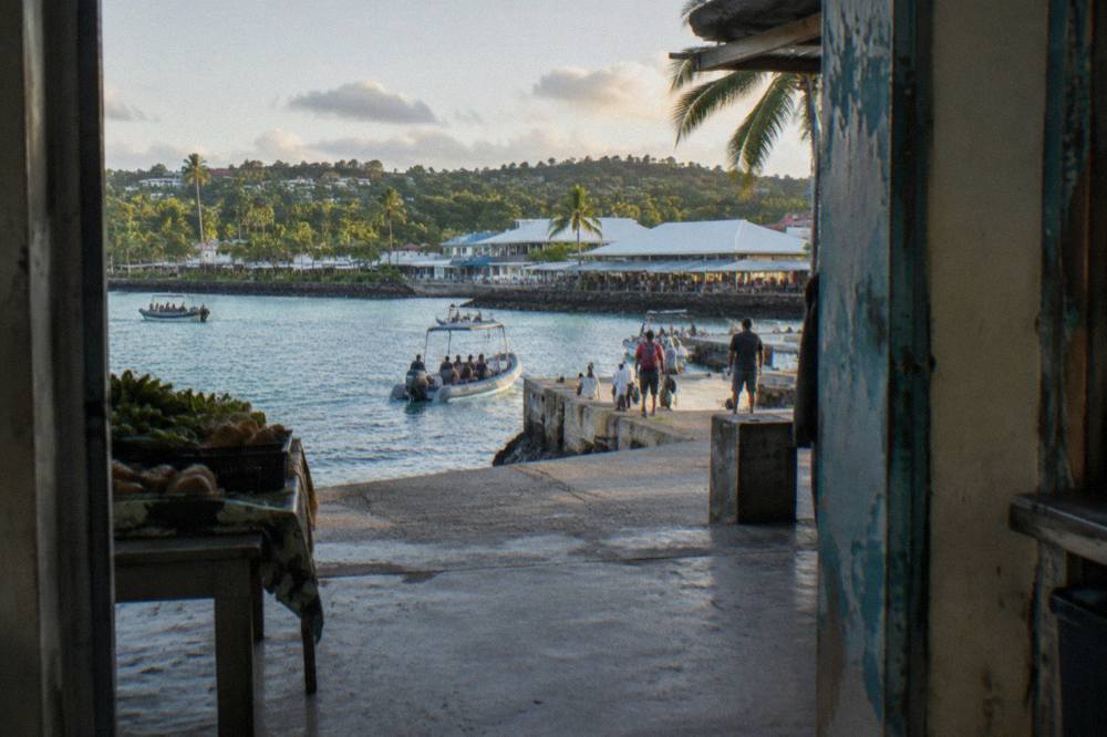 Tender boats arriving at the Port Vila seafront with the town market buildings behind the palm trees