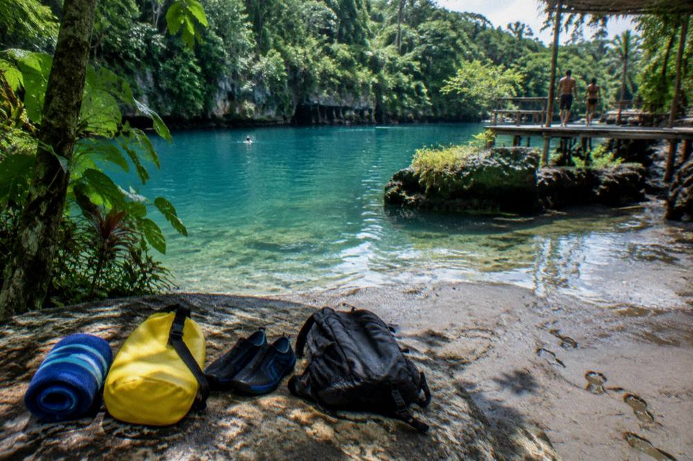 Towel, dry bag and water shoes laid out beside a day pack for a swimming trip