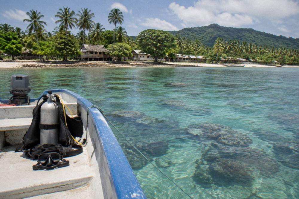 Small boat moored over clear shallow reef water