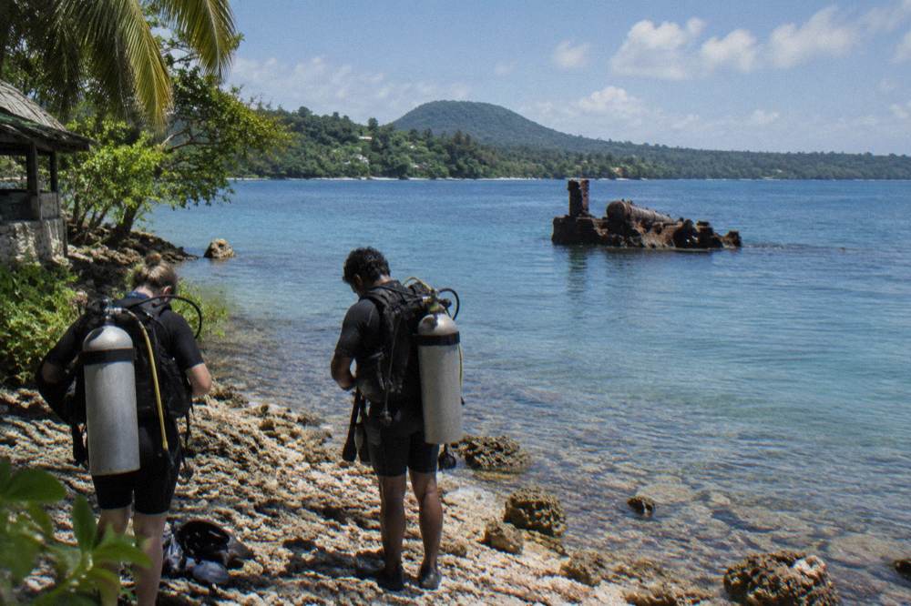 Divers preparing gear near a boat over calm sea