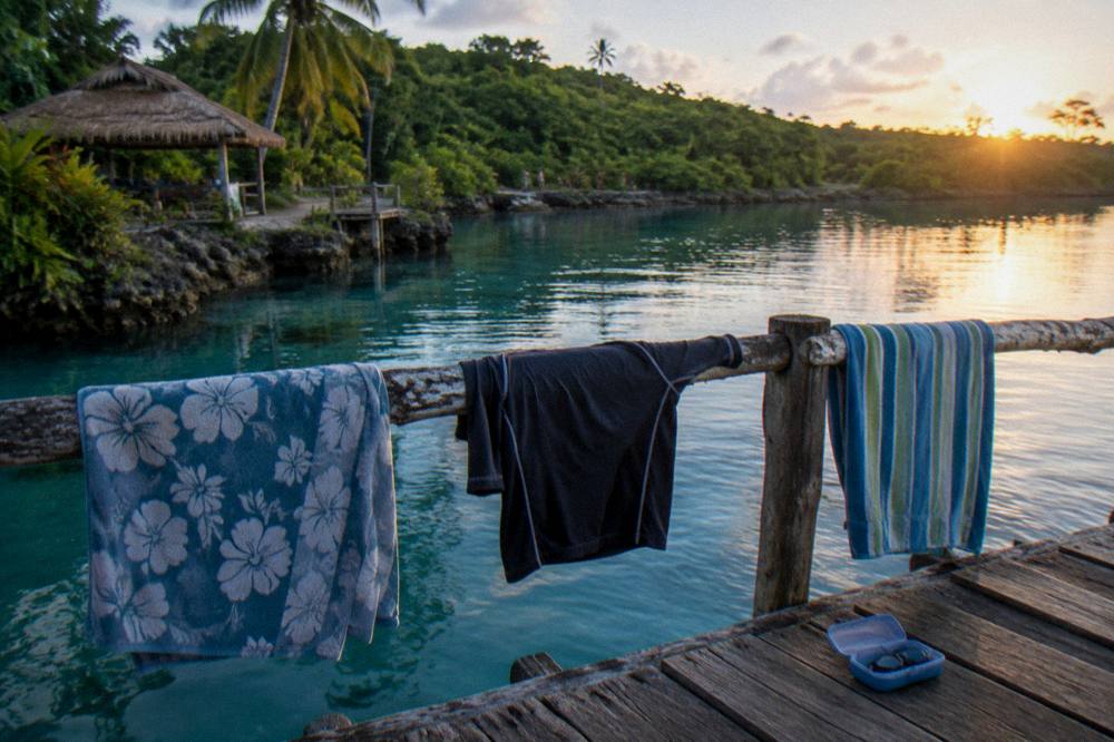 A tour group's towels drying on a railing above a calm blue lagoon at the end of the day