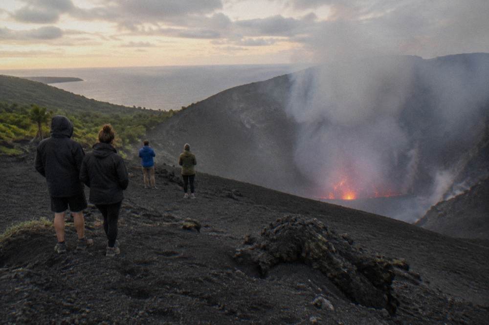 Visitors standing at a safe distance from the smoking crater edge of Mount Yasur
