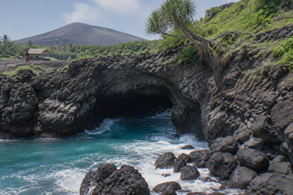 Coastal sea cave entrance on Tanna with turquoise water and dark volcanic rock