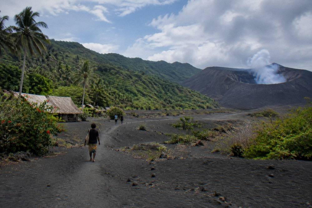 Volcanic landscape on Tanna with dark ash plains and vegetated slopes under scattered cloud